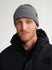 Man wearing a gray knit beanie and black jacket on a white background